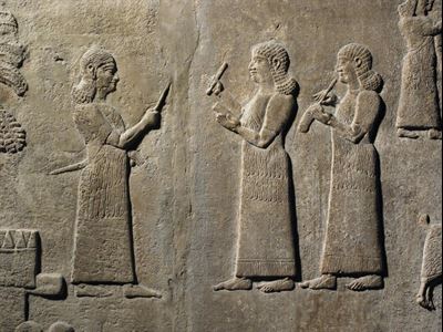 Assyrian scribes, one writing in cuneiform and the other writing in Aramaic (745–747 BC). Image via britishmuseum.org.