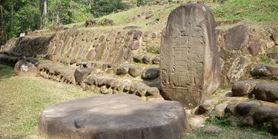 Stela 5 at Takalik Abaj, El Asintal, Retalhuleu, Guatemala, showing an early example of a Long Count date. Altar 8 lies before it. Image via wikimedia Commons.